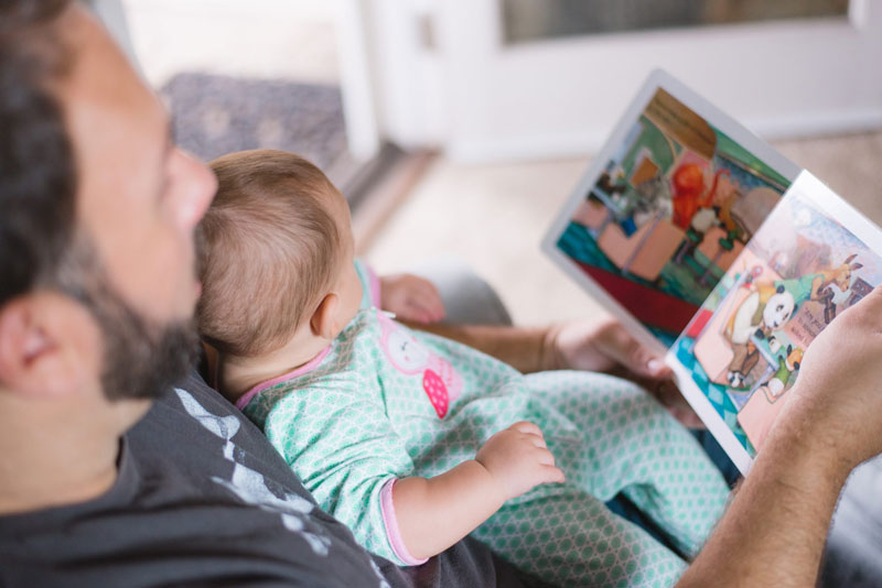 Father Reading Story Book to Baby